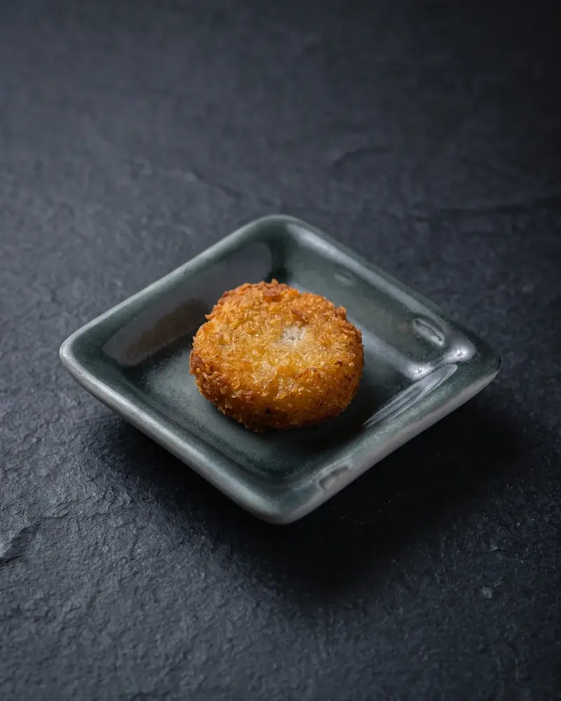Croquete empanado dourado em prato quadrado cinza